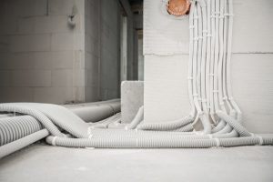 Detailní pohled na instalaci elektroinstalace a rozvodů v husích krcích na hrubé stavbě.